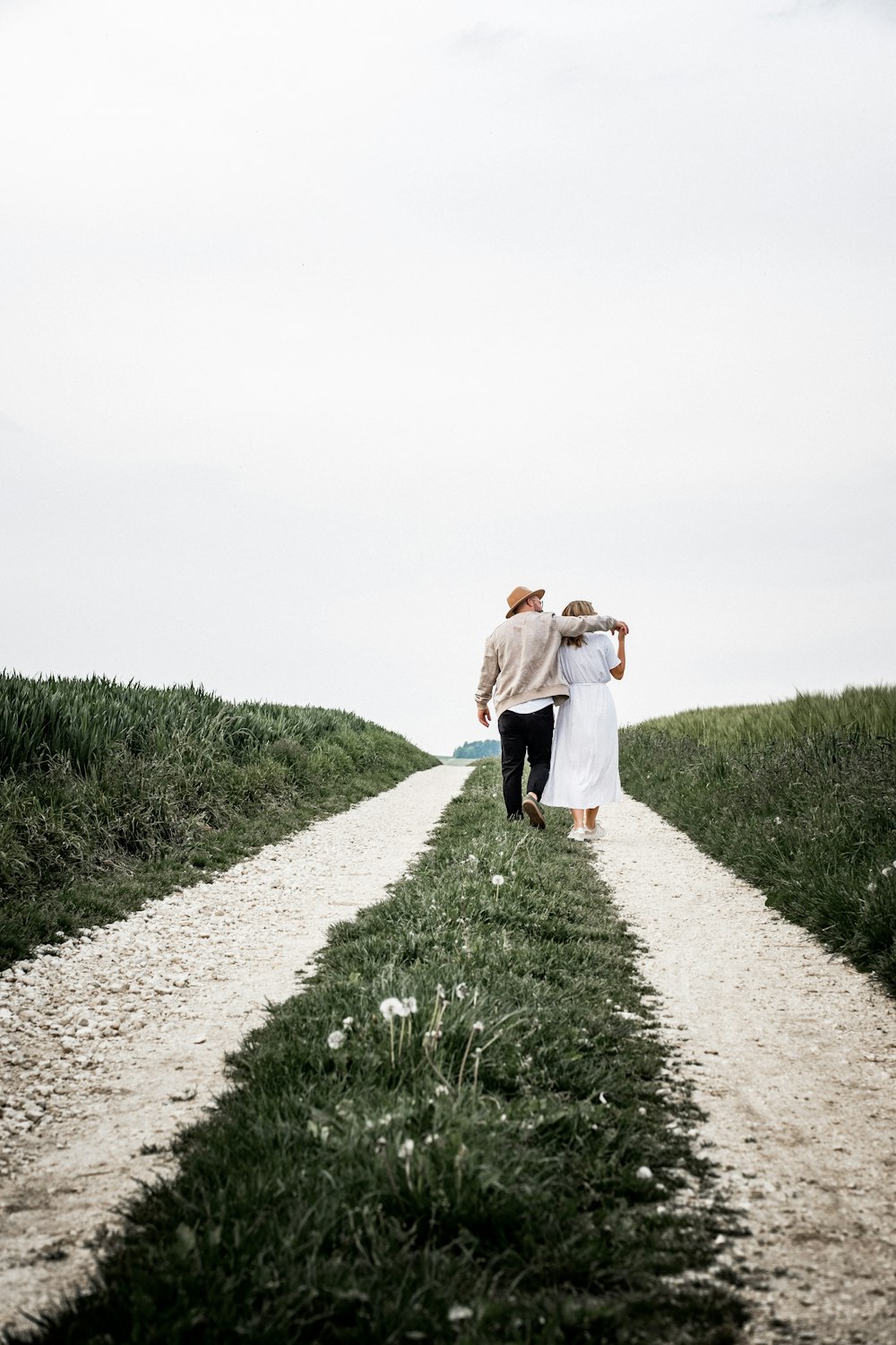 man and woman walking on pathway beside green bush