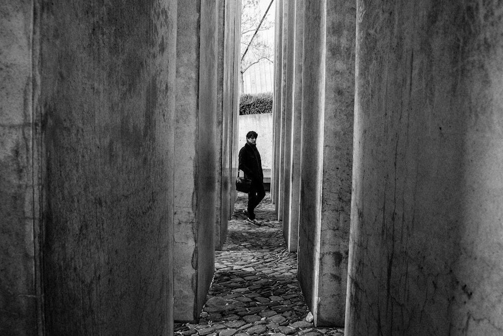 man walking between concrete pillars