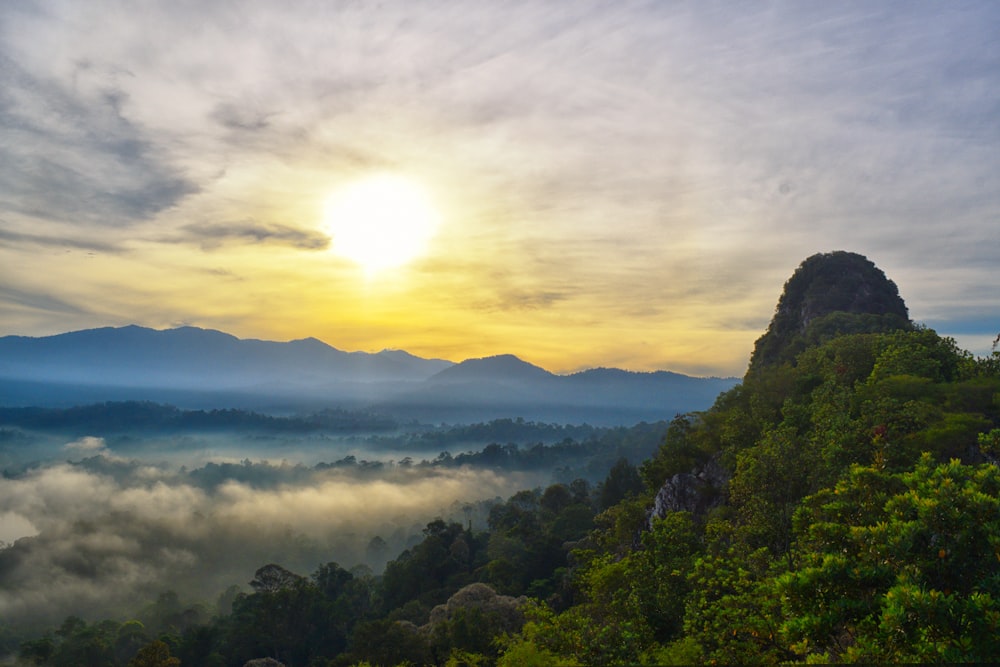 mountain covered with fogs under white skies