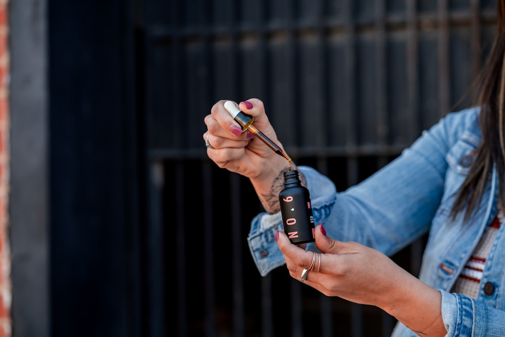 woman holding cosmetic drop bottle