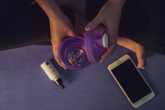 Close-up of hands gently rolling a yoga ball on a desk beside a laptop and water bottle.