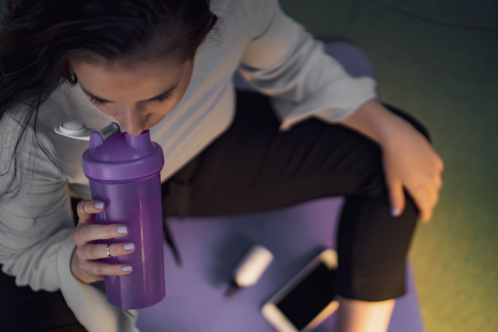 donna che sorseggia su un bicchiere viola