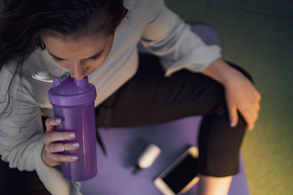 woman sipping on purple tumbler