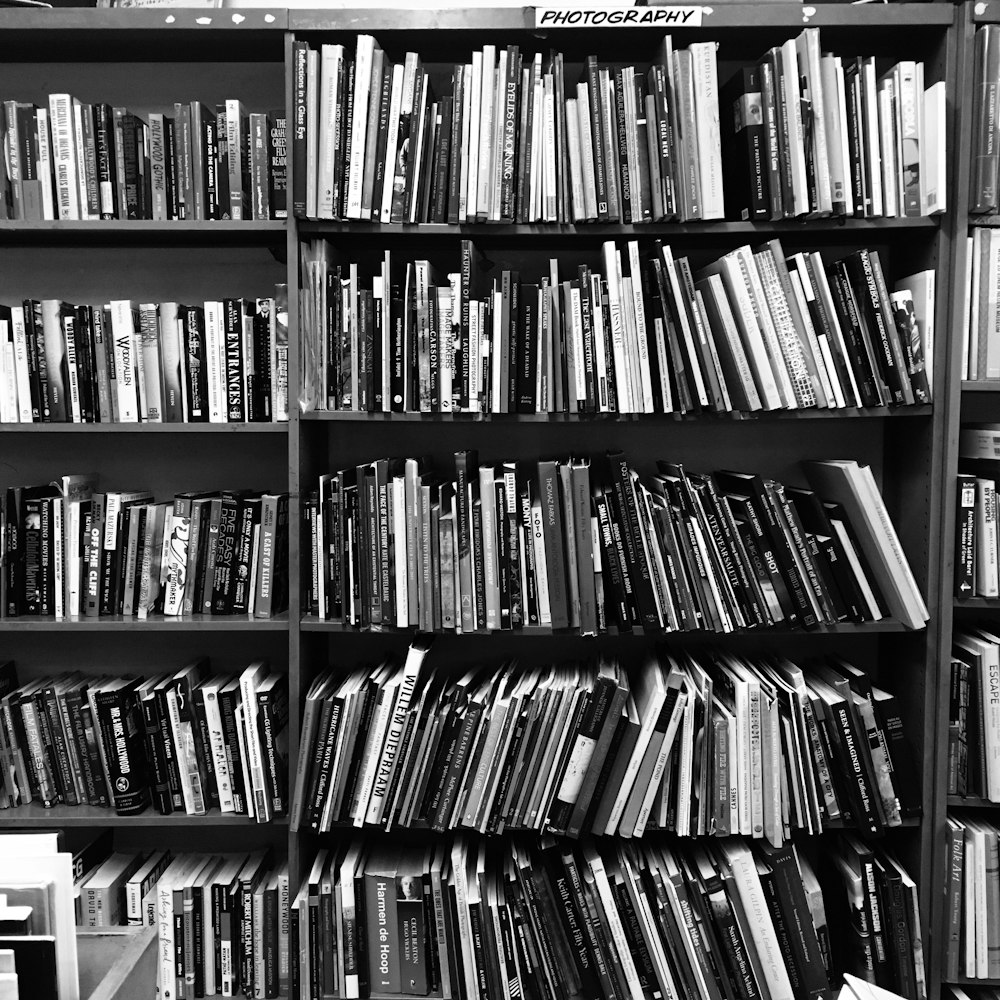 grayscale photo of books on a shelf