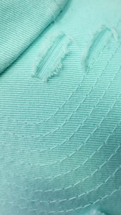 Close-up of a finely stitched sustainable blouse fabric in muted green tones.