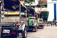 Colorful tuk-tuks lined up on a busy city street in Delhi.