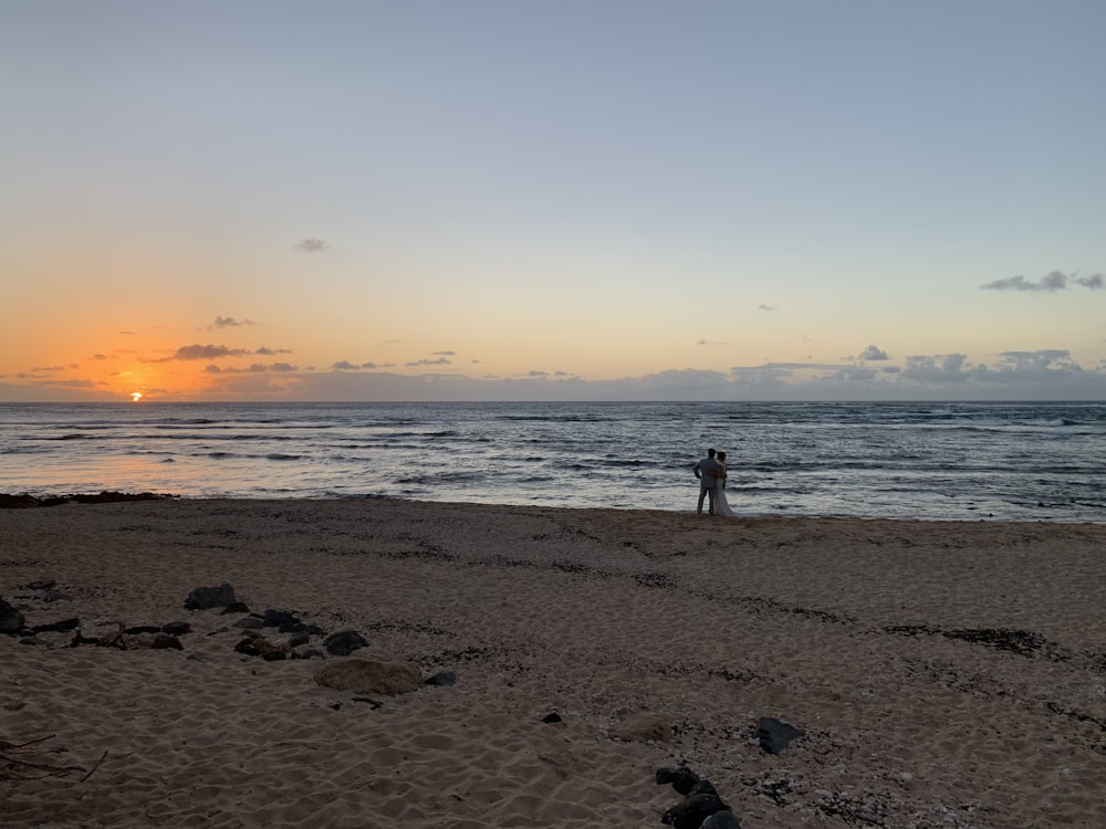 silhouette of man and woman standing beside seashore during daytime