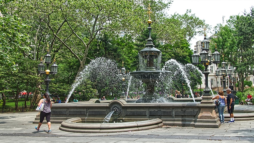 three persons standing beside water fountain