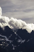 Dramatic clouds swirling above jagged mountain summits.