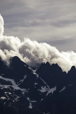 Dramatic clouds swirling above jagged mountain summits.