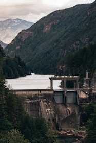 A sleek dam structure nestled in a misty mountain valley at dawn.