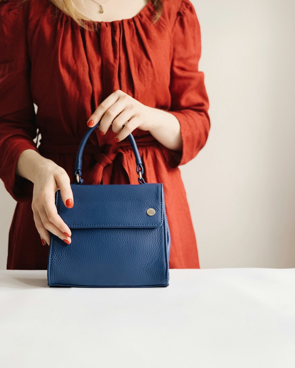 mujer sosteniendo bolso de cuero azul