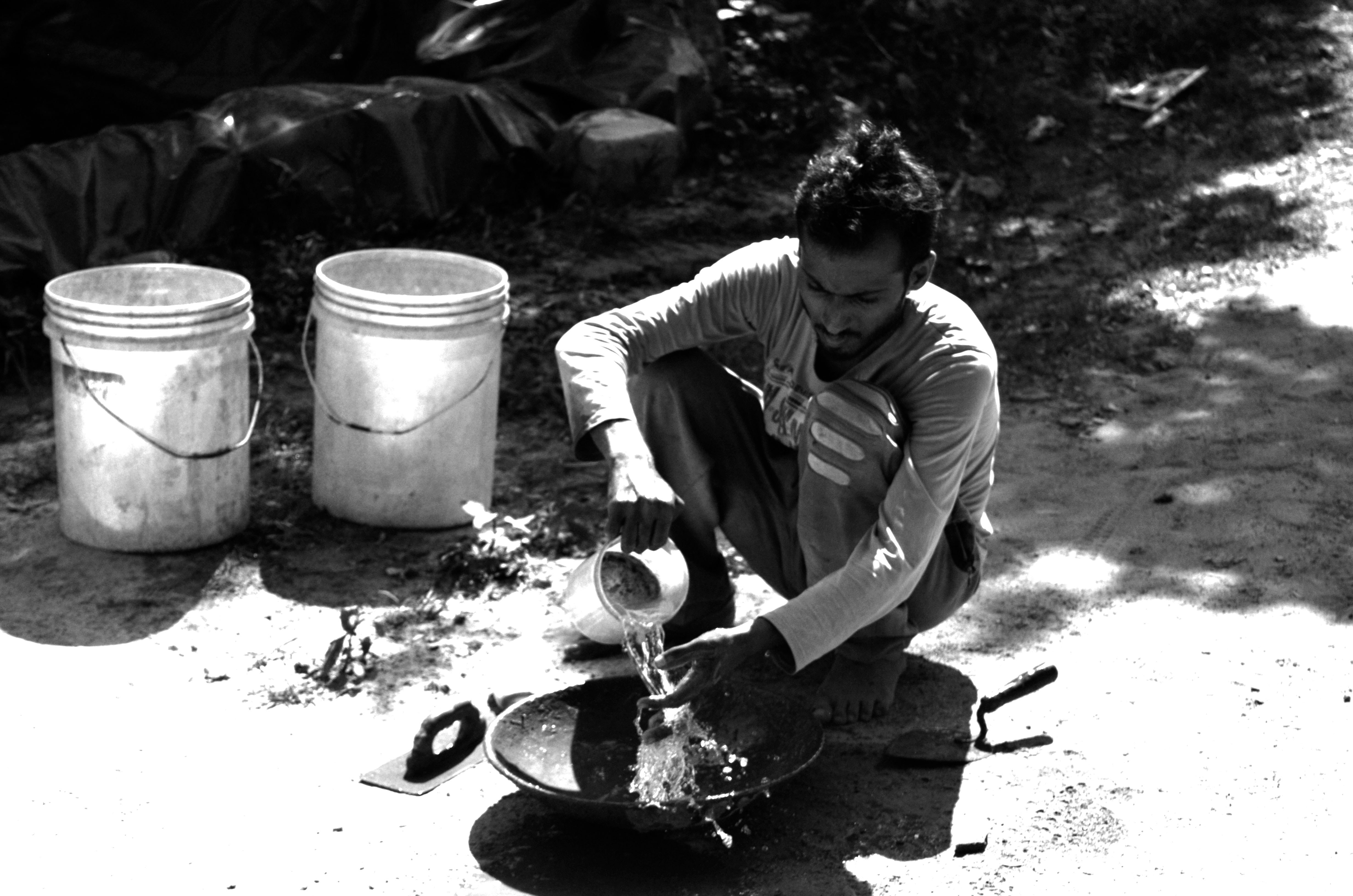 man cleaning wok near outdoor during daytime
