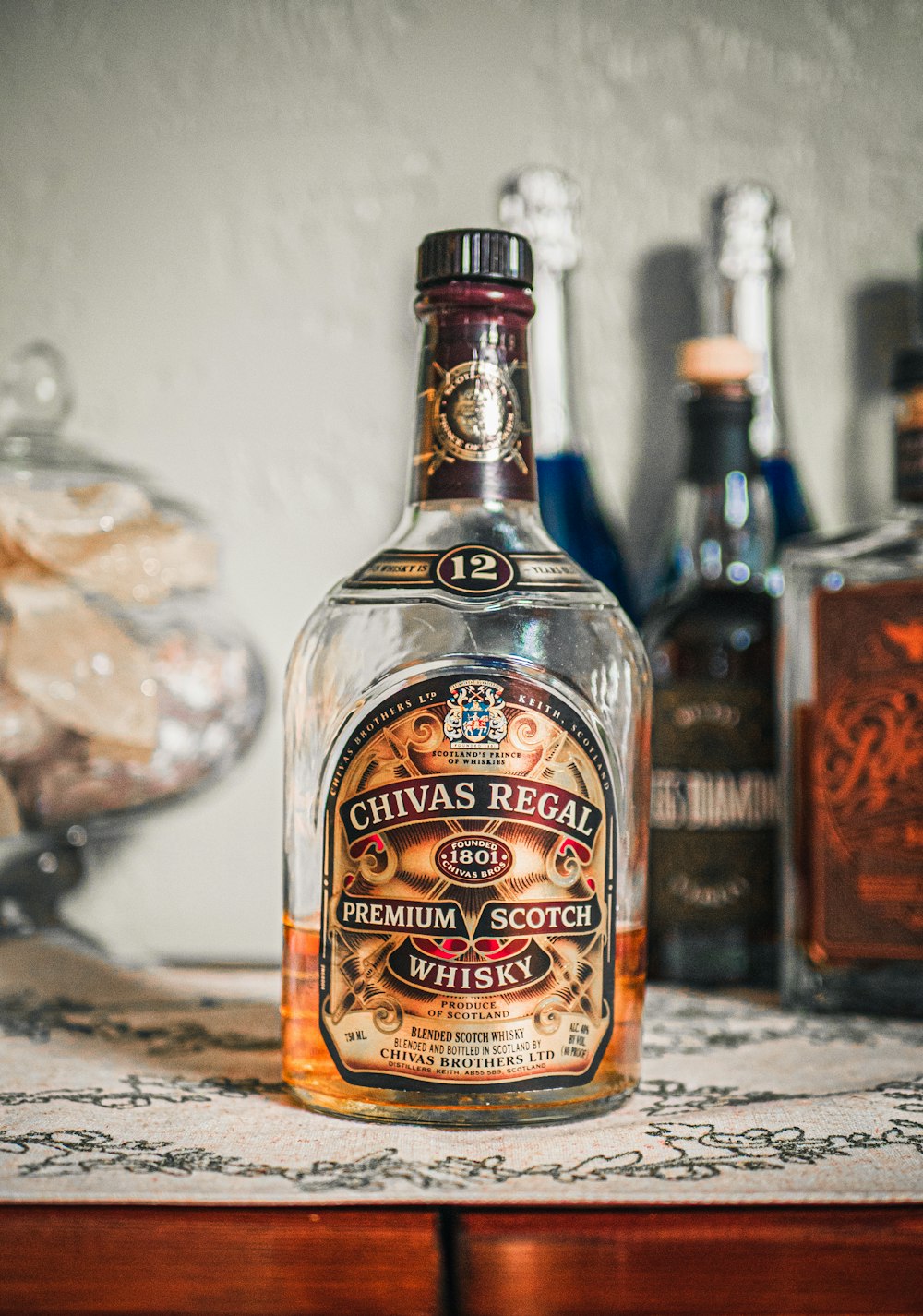 half-filled Chivas Regal Whisky bottle on sideboard