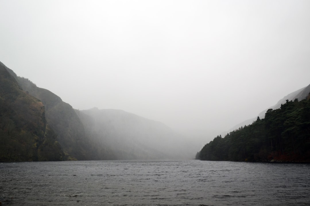 greyscale photography of body of water near mountain