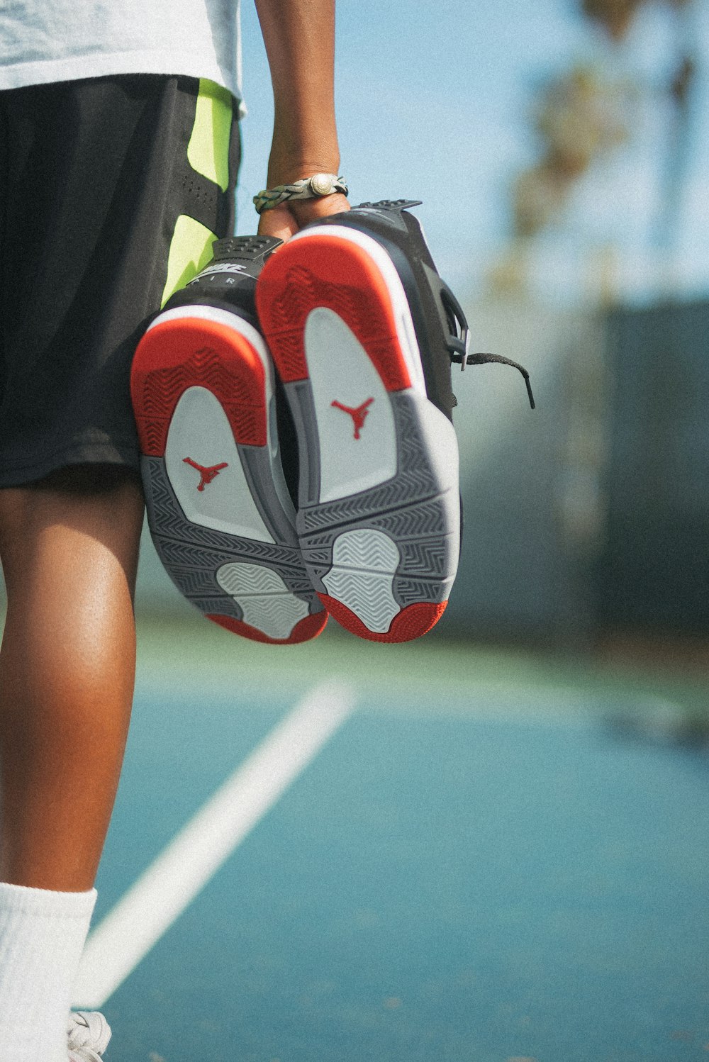 person holding orange,grey,white and black Air Jordan basketball during daytime close-up photography