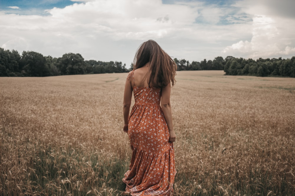 Mulher no vestido laranja no campo de trigo