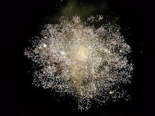 A dazzling burst of neon green and metallic gold fireworks lighting up a dark sky with smoky trails and sparks.