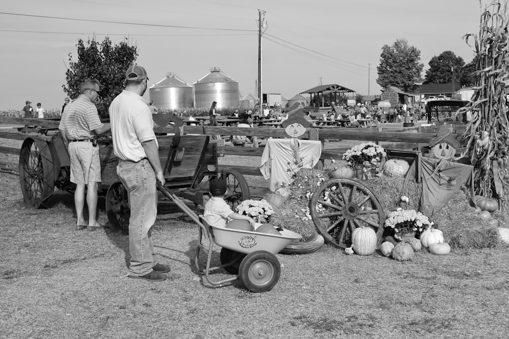 grayscale photography unknown person pushing wheelbarrow
