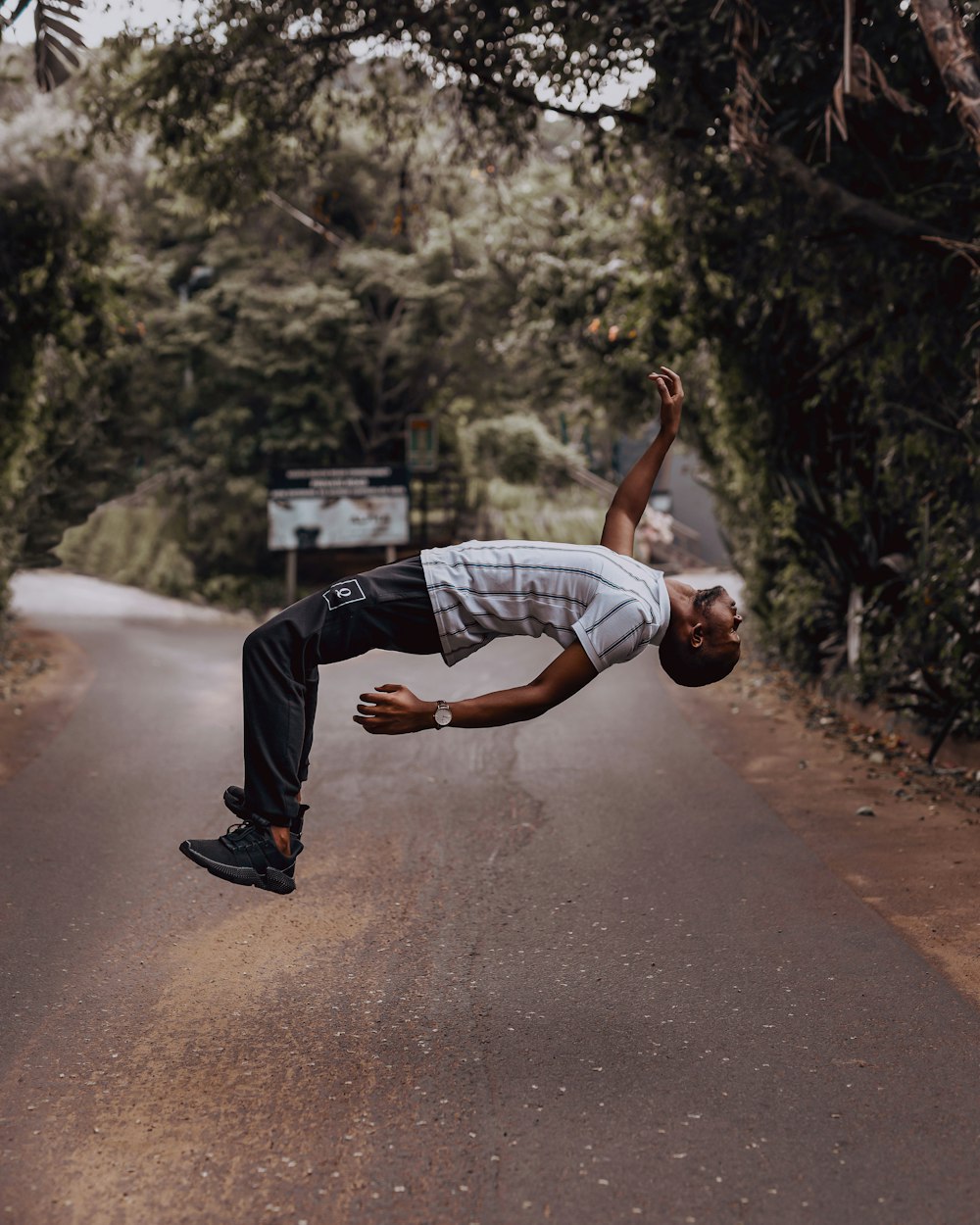 man in white and black striped top and black pants bending on road