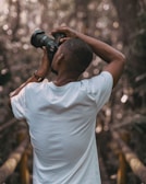 selective focus photography of a man in white t-shirt using a DSLR camera