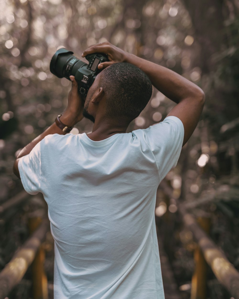 selective focus photography of a man in white t-shirt using a DSLR camera