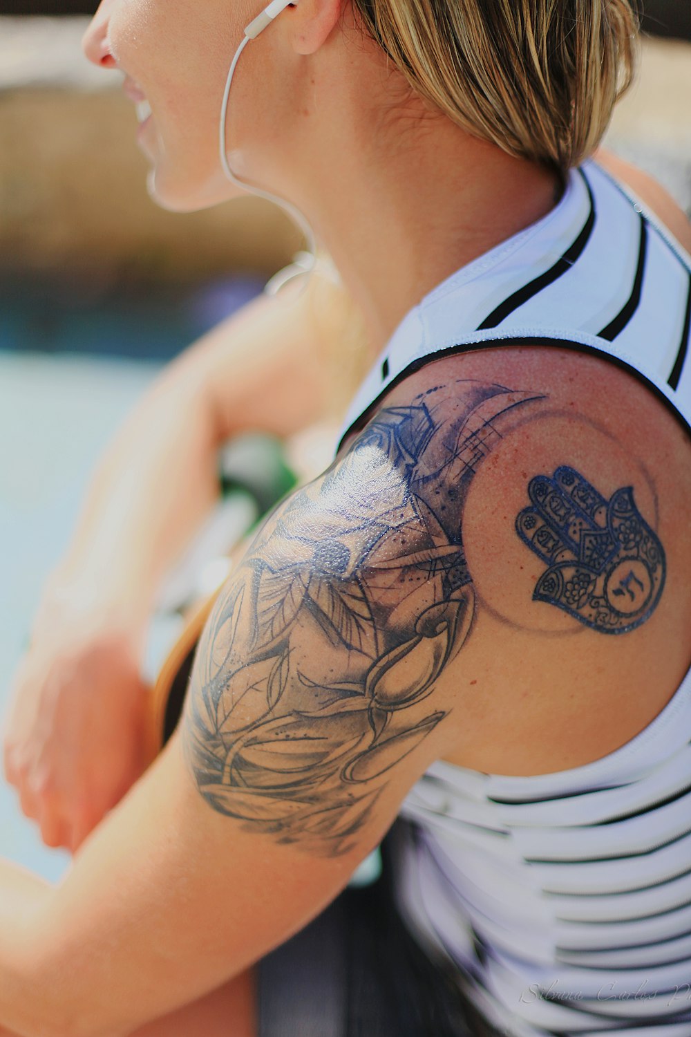 woman wearing white and black stripe tank top showing Hamsa hand tattoo