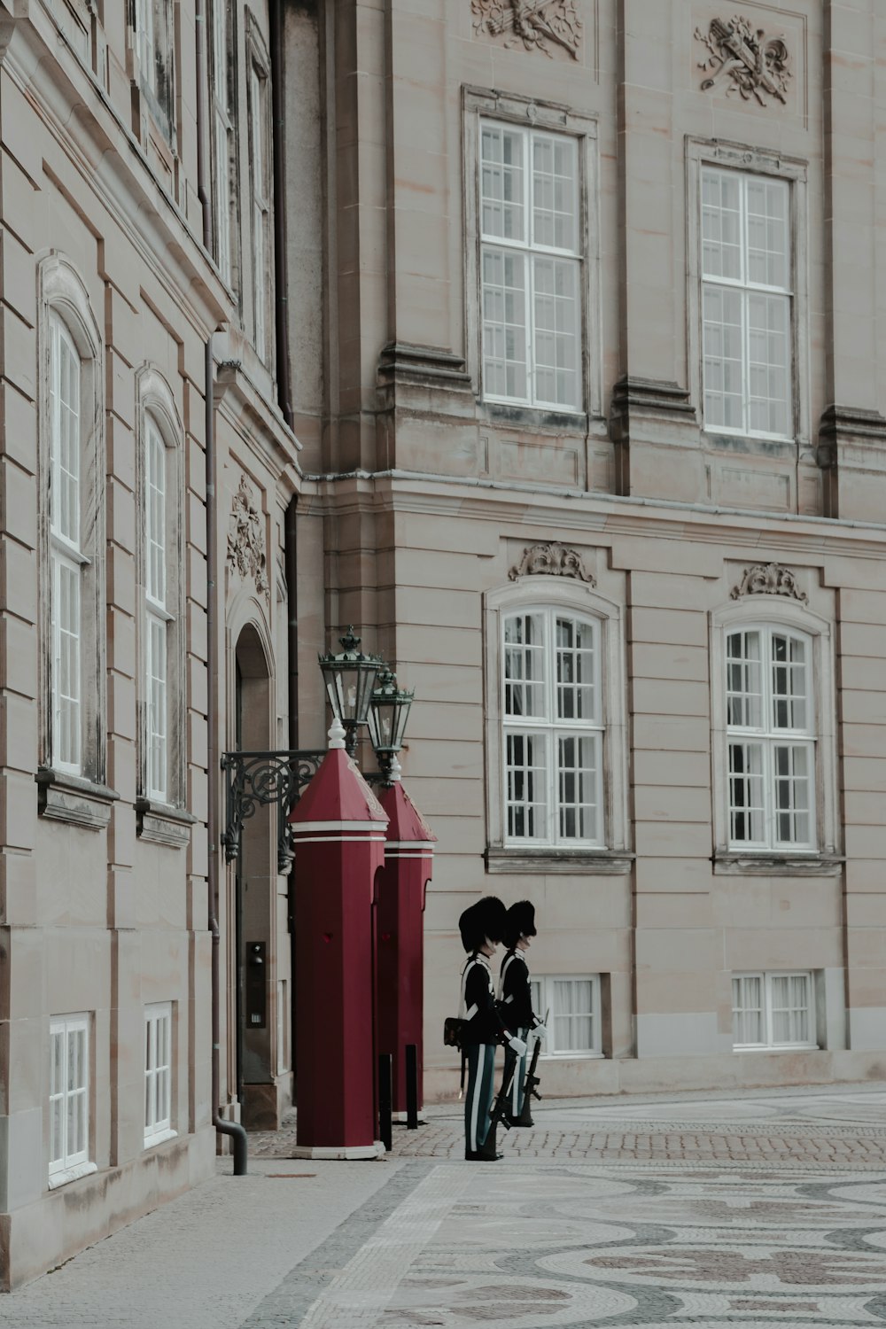 2 royal guards standing by concrete archway of building at daytime