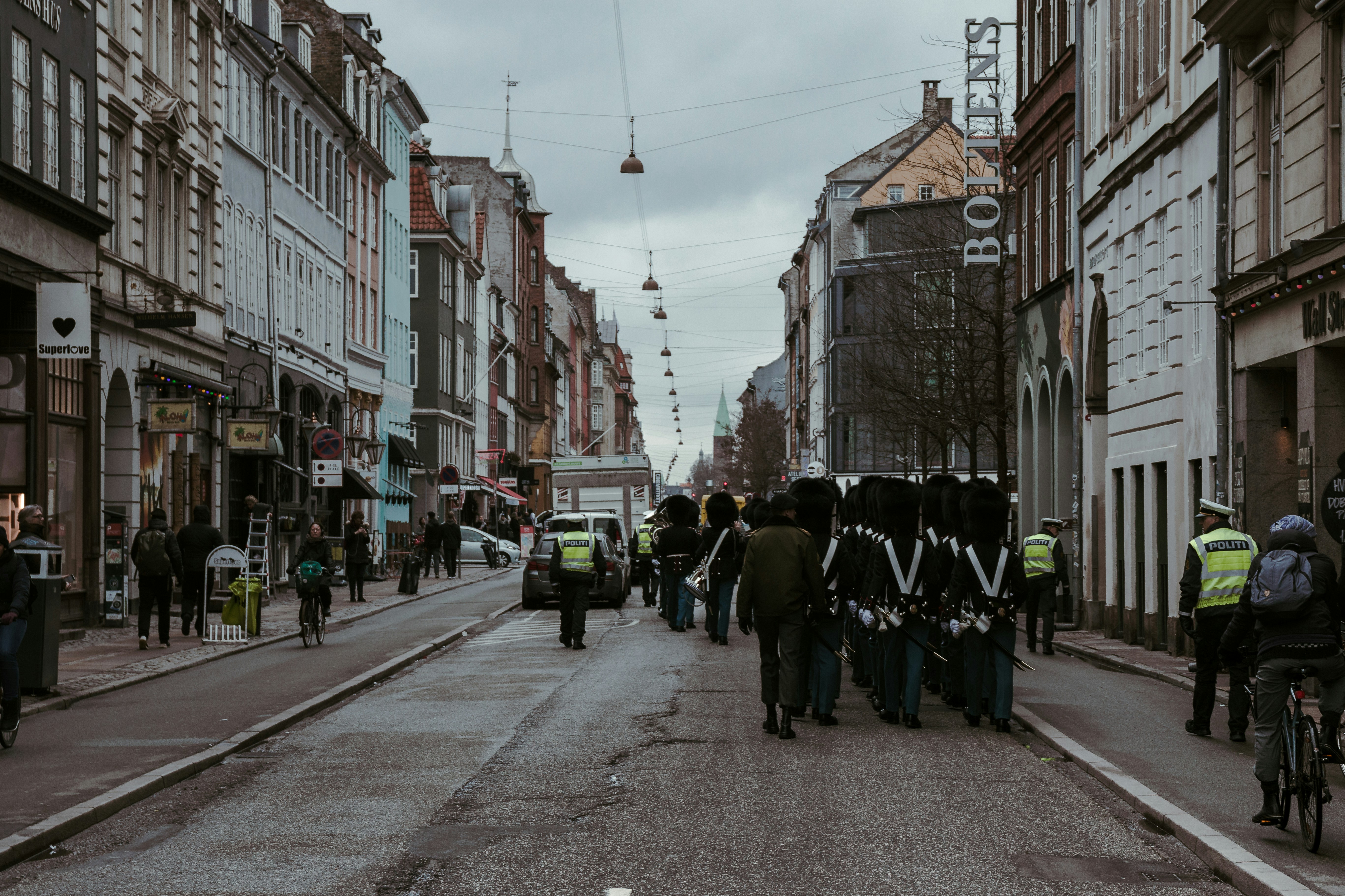 A street in a J-K town with residents looking towards a police vehicle, depicting a drill scenario where safety protocols are being demonstrated.