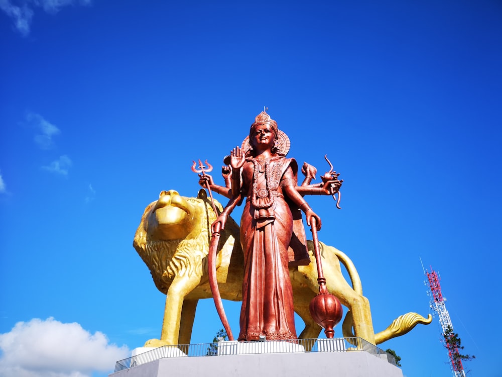 red Goddess Kali statue in front of gold lion statue during day