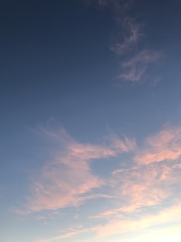 Soft pastel sky with gentle rays of sunlight breaking through fluffy clouds, evoking a sense of peace and hope.