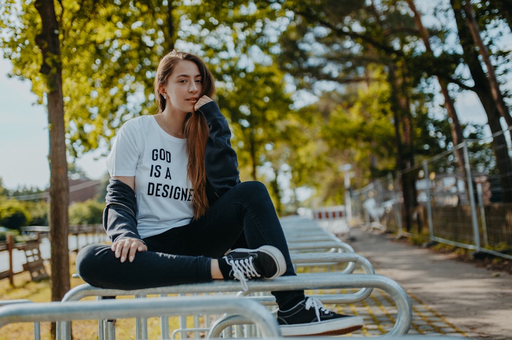 woman in white crew-neck t-shirt sitting on white metal railings