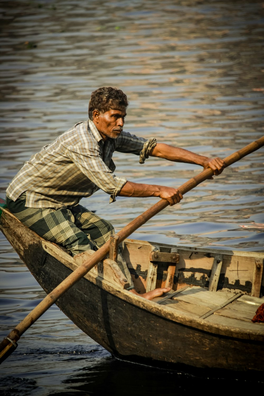 man wearing gray and white plaid dress shirt rowing boat