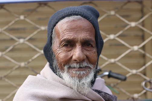 An elderly man receiving a warm blanket from a caring volunteer outdoors.
