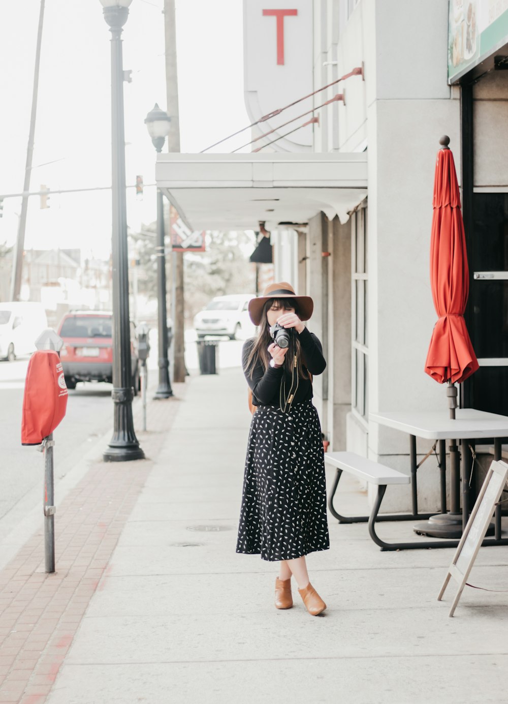 standing woman wearing black long-sleeved dress standing beside table