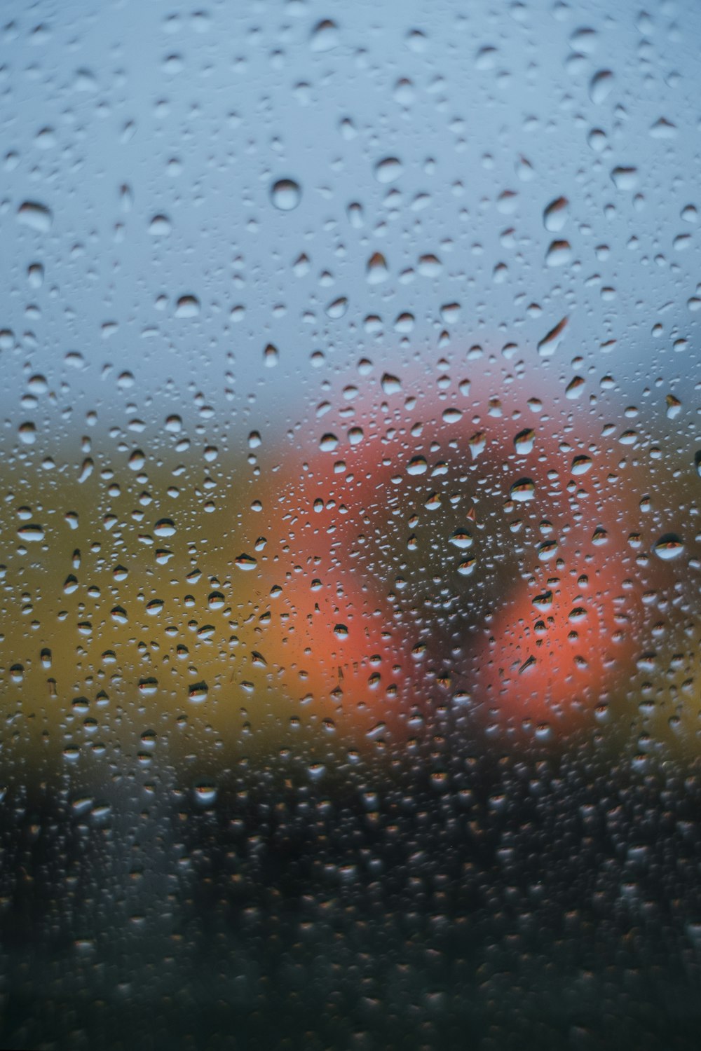 a rain covered window with a red object in the background