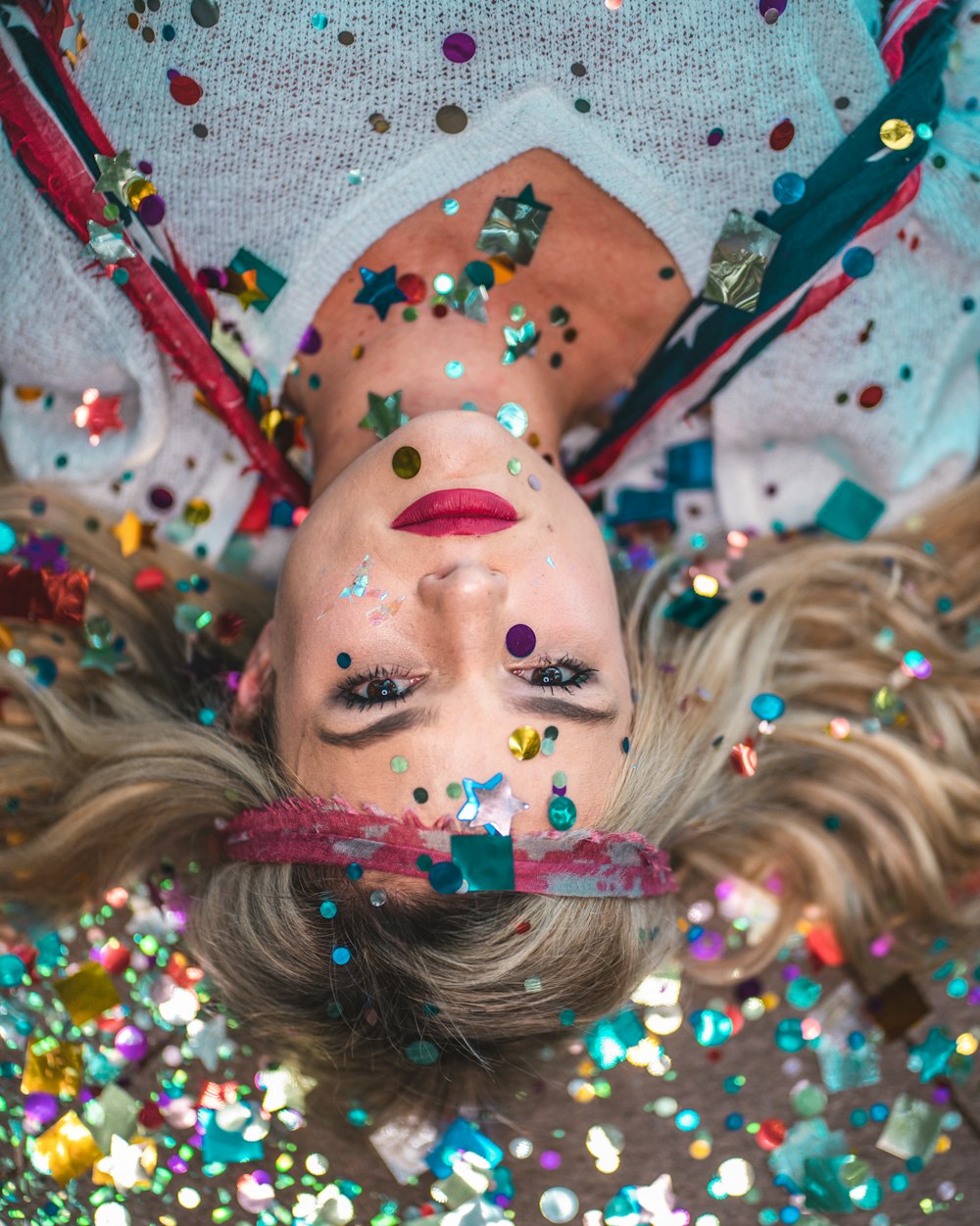 woman in white top covered with confettis while on floor