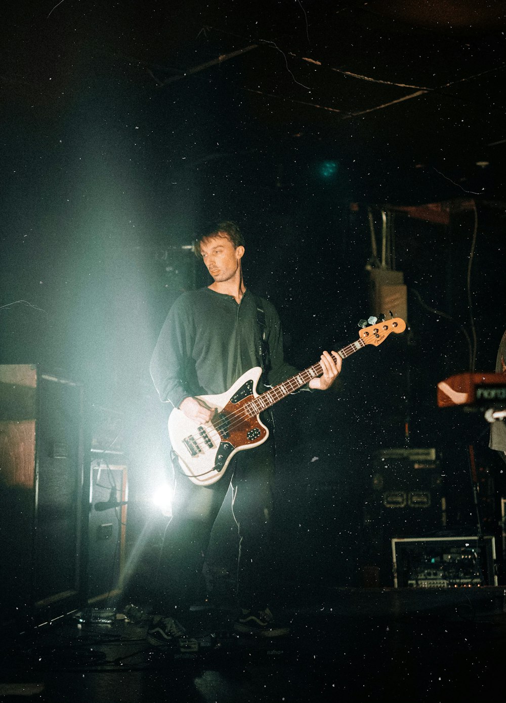 man playing guitar by amplifiers