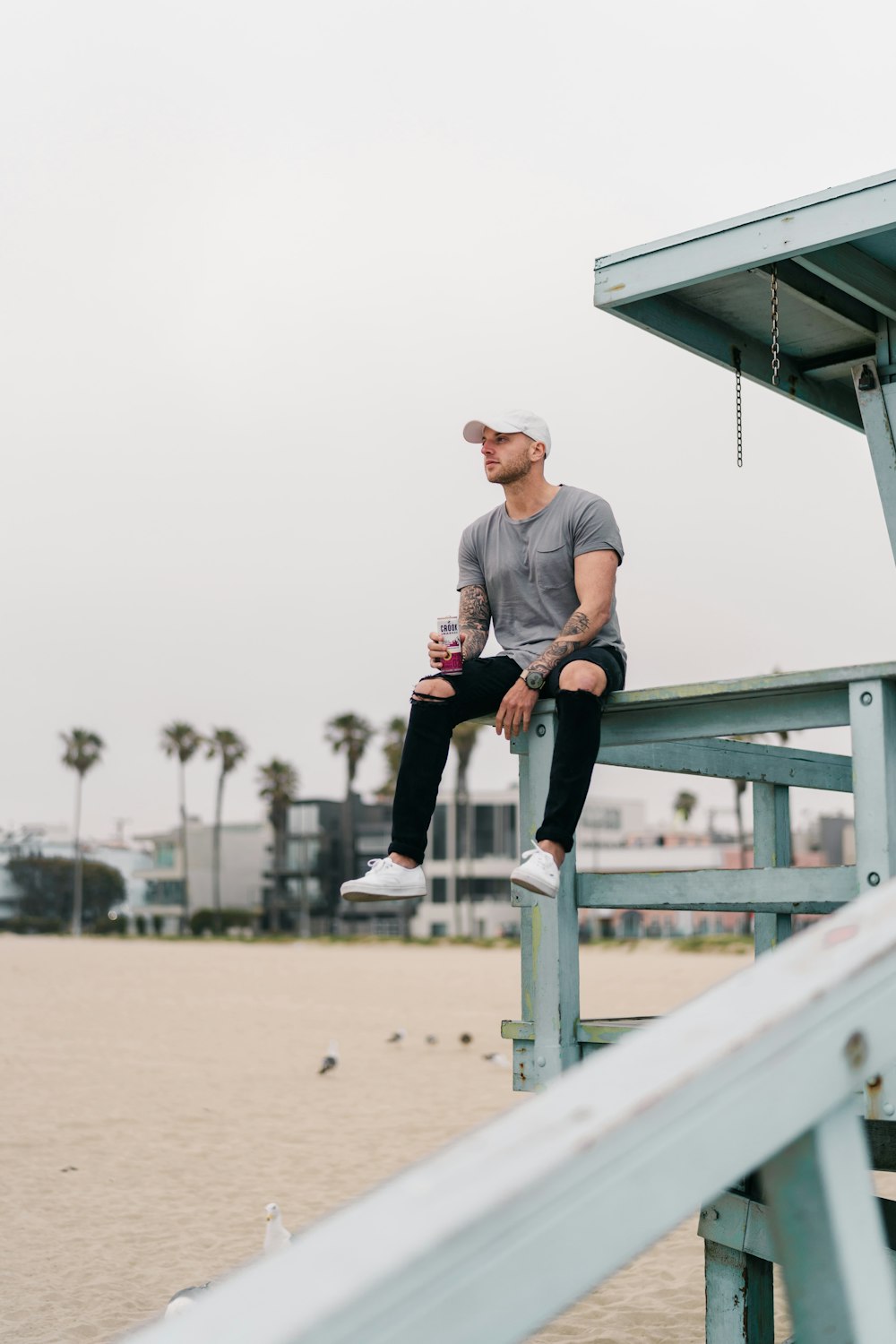 man sitting on grey wooden railing