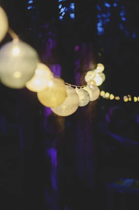 Warm LED string lights glowing softly above a cozy outdoor seating area at dusk