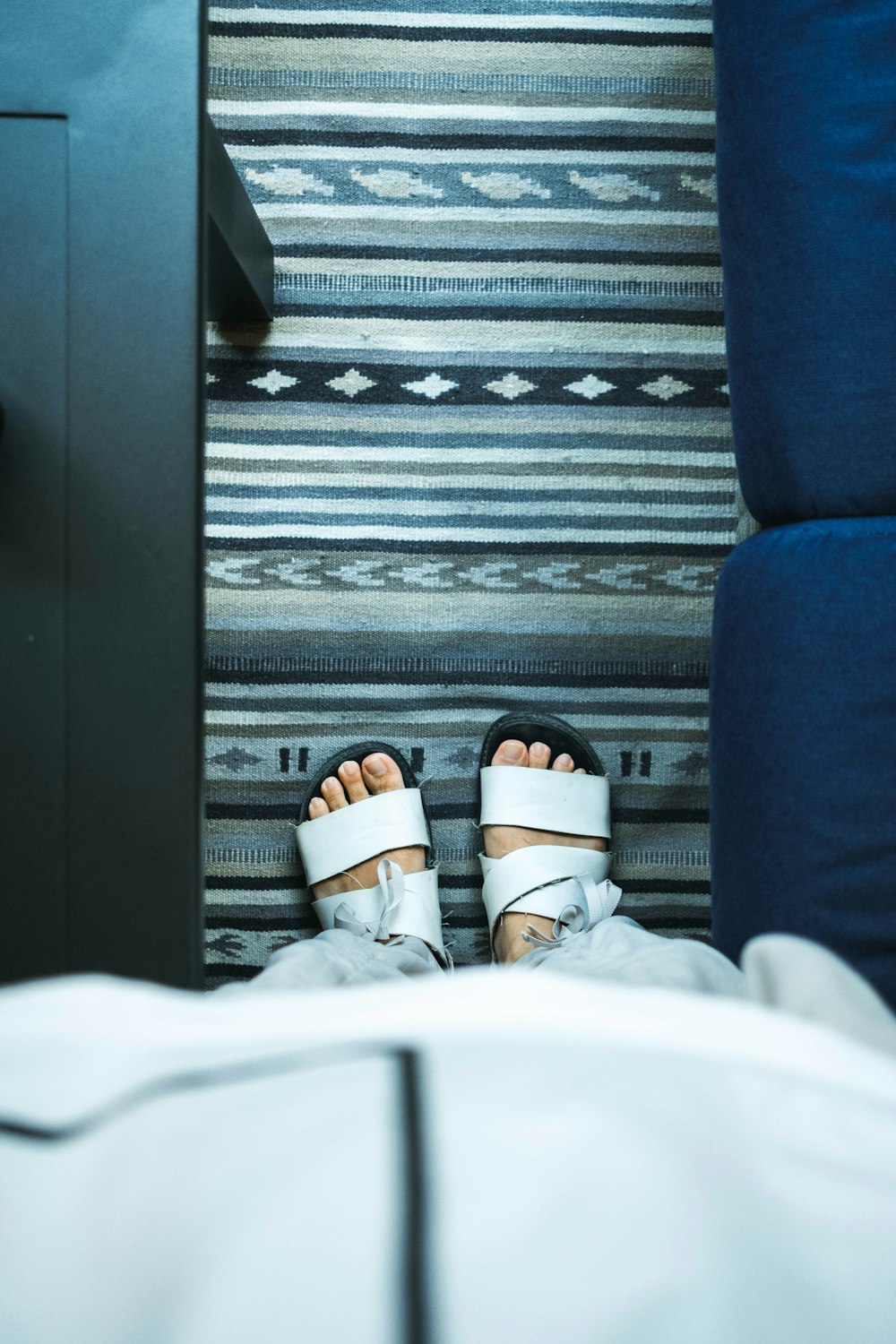 a person's feet in sandals on a bed