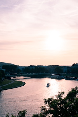 A serene river cruise boat gliding past lush green landscapes under a golden sunset.