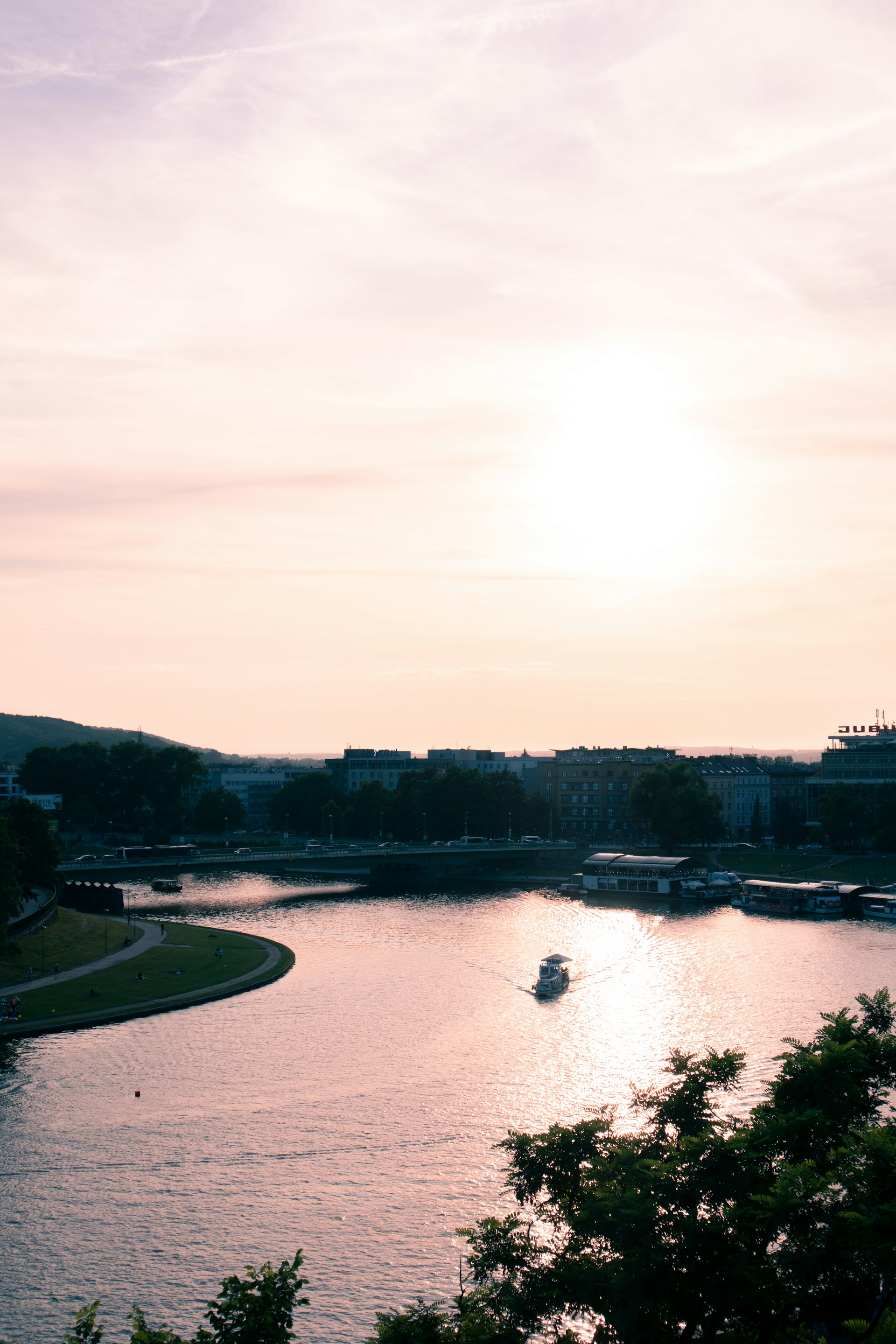 Sunset over a serene river where a small boat floats gently, inviting travelers to experience peaceful moments in nature with Kameng Adventures.