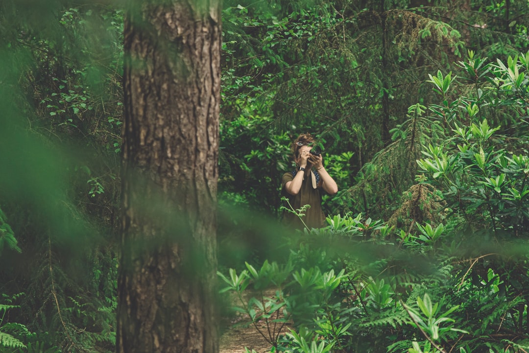 woman in green dress taking picture in the woods