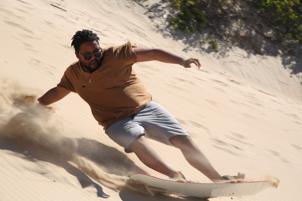 man sliding down sand dunes