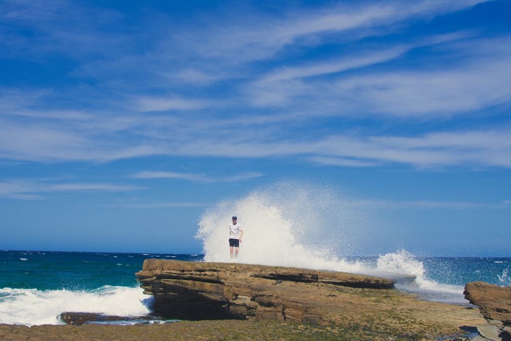 person standing on rock under blue sky