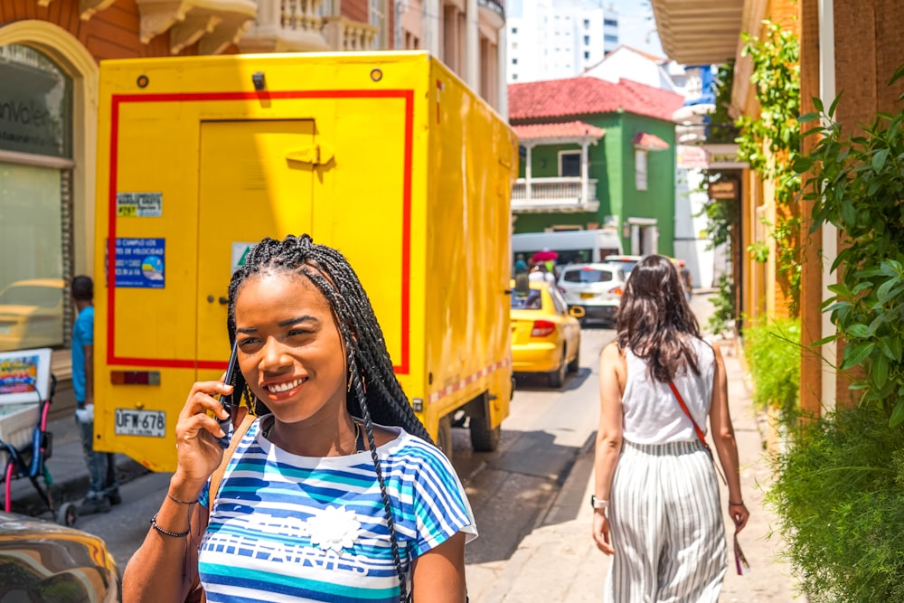 woman holding smartphone beside yellow box van