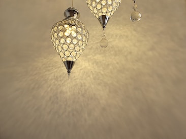 Two ornate pendant lights with a geometric lattice design, casting intricate patterns on the ceiling and wall. The lights have a warm, golden glow and are embellished with small hanging crystals.
