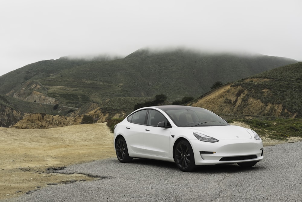 white sedan parked beside mountain during daytime