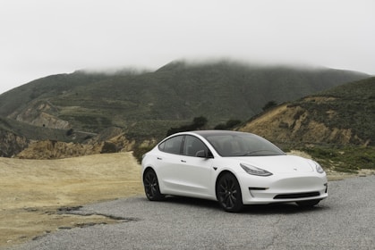 white sedan parked beside mountain during daytime